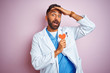 © Krakenimages.com - Young indian doctor man holding paper heart standing over isolated pink background stressed with hand on head, shocked with shame and surprise face, angry and frustrated. Fear and upset for mistake.