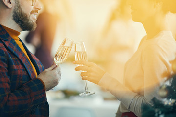 Wall Mural - Closeup of adult couple drinking champagne and talking during Christmas banquet, golden lens flare overlay