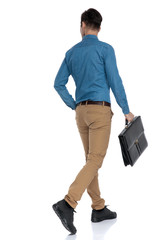 Poster - back view of smart casual man walking and holding suitcase