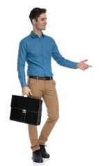 Canvas Print - young elegant man holding suitcase and presenting to side