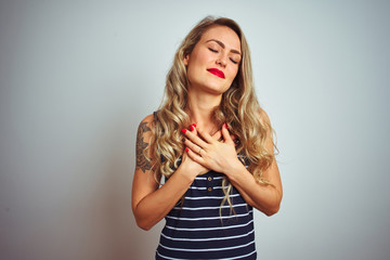 Sticker - Young beautiful woman wearing stripes t-shirt standing over white isolated background smiling with hands on chest with closed eyes and grateful gesture on face. Health concept.