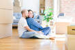 © Krakenimages.com - Young couple sitting on the floor arround cardboard boxes moving to a new house looking to side, relax profile pose with natural face with confident smile.