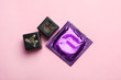 Sex dice and condom on pink background, top view