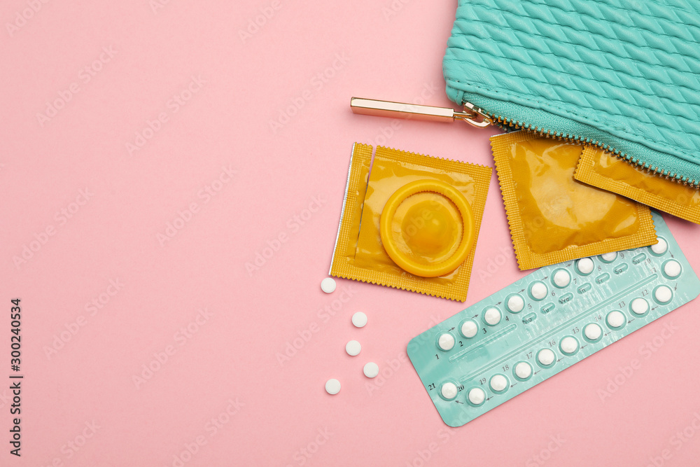 Condoms and birth control pills in purse on pink background, top view with space for text. Safe sex - obrazy, fototapety, plakaty 