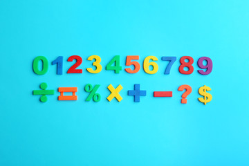 Colorful magnetic numbers and math symbols on light blue background, flat lay