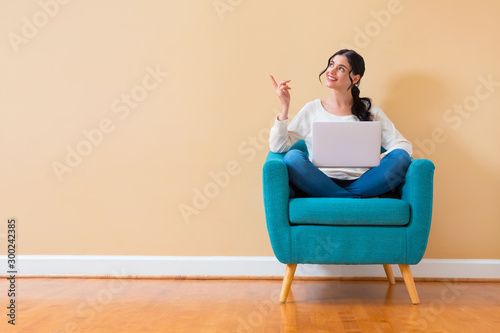 Fotografía Young woman with a laptop computer pointing something sitting in a chair