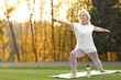 © New Africa - Happy mature woman practicing yoga in park. Active lifestyle
