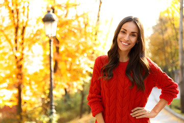 Wall Mural - Beautiful woman wearing red sweater in sunny park. Autumn walk