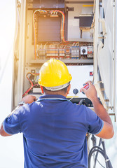 Canvas Print - Electrician with yellow safety helmet screwing equipment repairing in fuse circuit breaker box