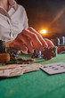 © Anton - croupier raises bets with chips. casino, playing at night, gaming business. victory and success, big money. vertical shot