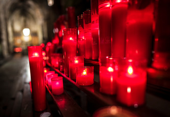 This image capture shows beautiful red, glowing prayer candles as they burn on an alter at night time in a Cathedral.