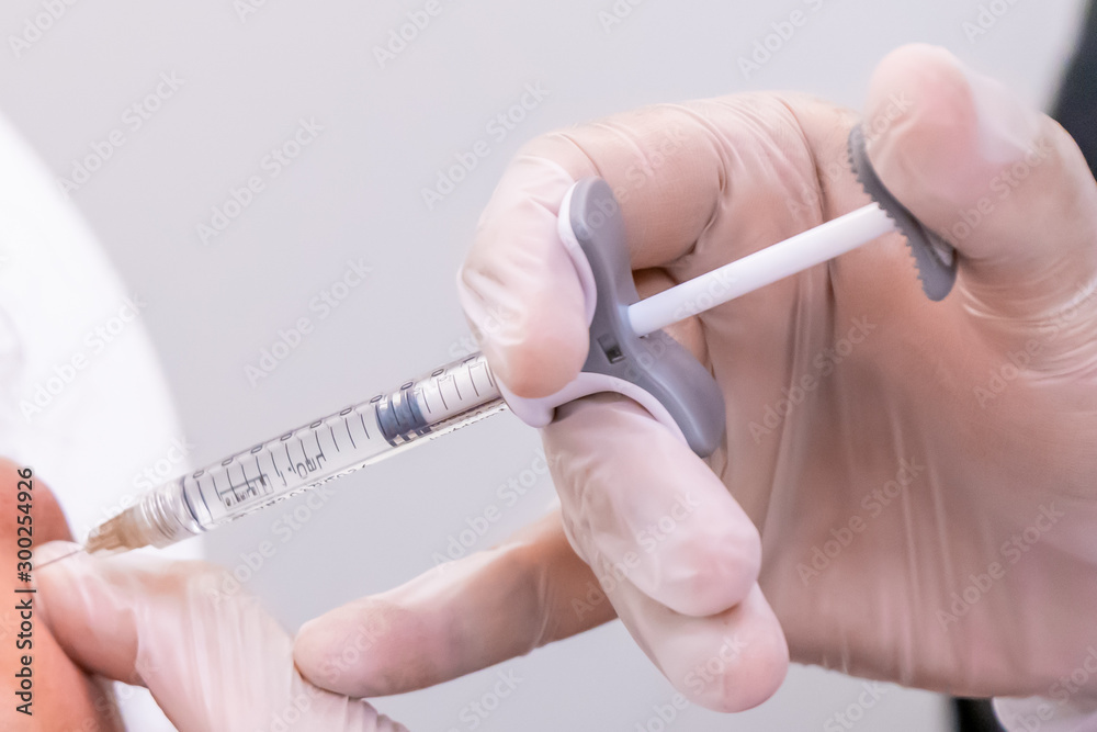 Hydo Injection Into Hand Gloved doctor hand injecting a vial of hyaluronic acid (HA) based ...