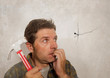© TheVisualsYouNeed - funny portrait of man holding hammer after driving a nail for hanging a frame but making a mess cracking the wall as a disaster DIY guy and messy domestic repair task
