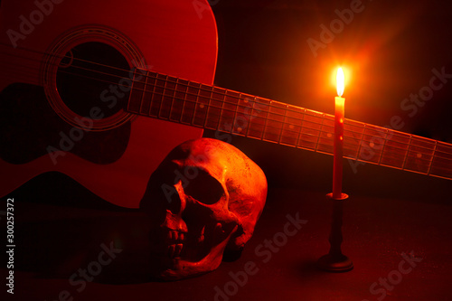 Fotomural Human skull and guitar in candlelight on a wooden table