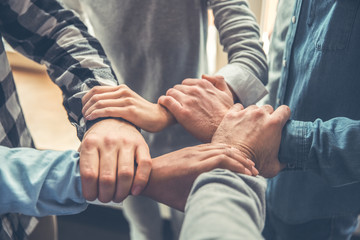 Startupers working at office together standing holding hands of each other support