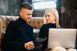 © Strelciuc - Beautiful young couple looking on to another smiling while holding a tablet and a laptop on the legs sitting on the floor at home.