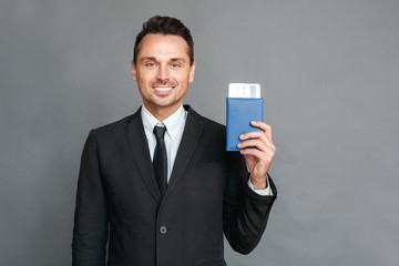 Wall Mural - Businessman studio standing isolated on grey with passport and ticket smiling toothy