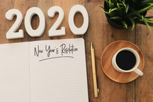 Business Concept Of Top View 2020 Year's Resolution List With Notebook, Cup Of Coffee Over Wooden Desk