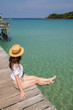 © allenkayaa - Young woman in a hat sits on a pier near the clear turquoise sea