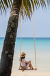 © allenkayaa - A woman in a hat on a swing on the shore of the turquoise sea