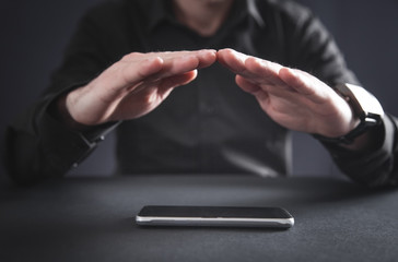 Man with protect gesture. Smartphone on the desk