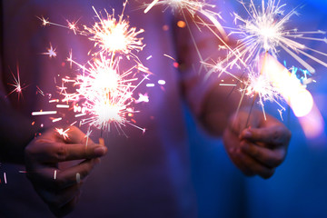 Poster - Hand of woman holding firework firework pyrotechnics and bokeh with blurry effect on the dark background for celebration concept