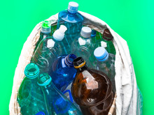 Simple Plastic Bottles In A Eco Bag On A Green Background, Recycling Concept