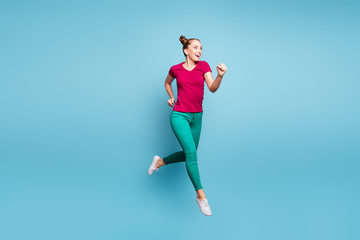 Poster - Full length body size photo of cheerful hurrying urgent girl wearing green pants footwear running jumping isolated over blue pastel color background