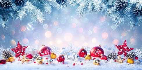 Wall Mural - christmas - red and golden baubles on snow with fir branches