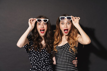 Wall Mural - Portrait of two shocked women hugging and looking at camera