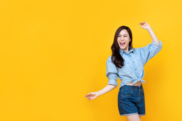 Wall Mural - Excited pretty Asian woman smiling with arm raise