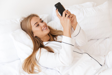 Sticker - Photo of attractive cheerful woman using cellphone while lying on bed