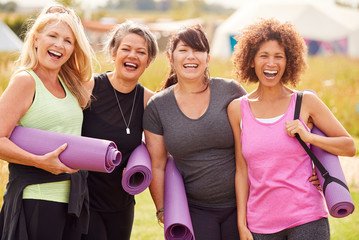 Wall Mural - Portrait Of Mature Female Friends On Outdoor Yoga Retreat Walking Along Path Through Campsite