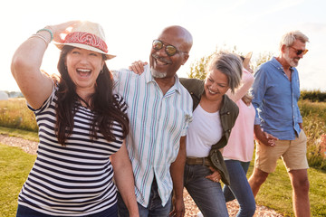 group of mature friends on vacation walking along path through campsite at sunset