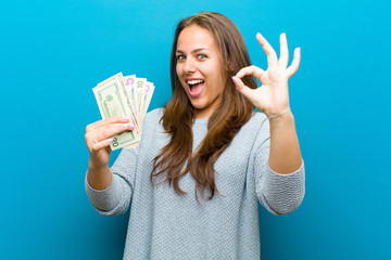 Wall Mural - young woman with bills against blue background