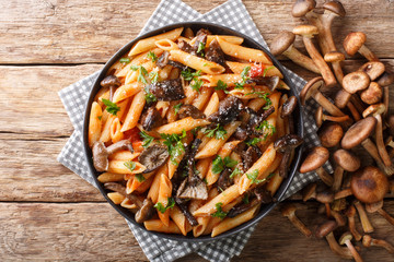 Wall Mural - Italian hot pasta with roasted honey mushrooms, parmesan and tomato sauce close-up in a plate. Horizontal top view