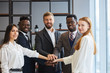 © alfa27 - Portrait of handsome good-looking business partners joining hands in pile and looking at camera. African, caucasian business people, colleagues. Confident people