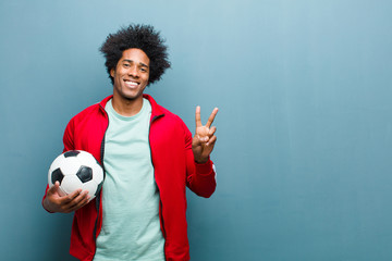 Wall Mural - young black sports man with a soccer ball against blue grunge wa