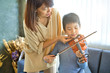 Asian kid learning and practising  to play violin at home