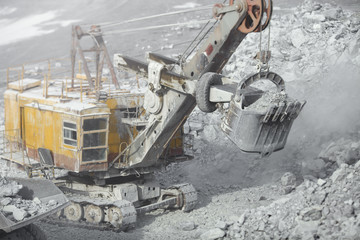 Poster - Excavator in a quarry during loading dump-body truck, close-up, tilt-shift lens effect. Quarry equipment. Mining equipment.