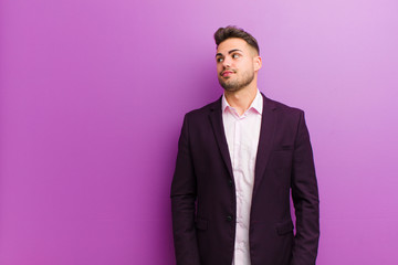 Wall Mural - young hispanic man wondering, thinking happy thoughts and ideas, daydreaming, looking to copy space on side