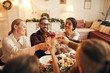 © Seventyfour - High angle portrait of cheerful adult people clinking champagne glasses while enjoying Christmas dinner at home, copy space