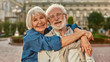 © Kostiantyn - I love my husband. Portrait of cheerful senior couple in casual clothing embracing each other and looking at camera with smile while standing together outdoors