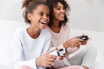 Wall Mural - Image of american woman and little girl playing video games with joysticks