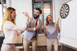 © Mediteraneo - Business people making team training exercise during team building seminar, play darts. Indoor team building activities.