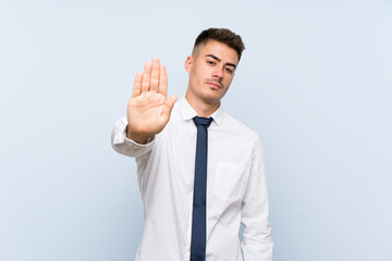 Handsome businessman over isolated blue background making stop gesture with her hand