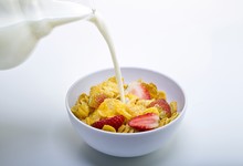 Milk Being Poured Out Of A Jar Into A Bowl Of Cereal And Strawberries