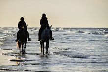 Two Horse Riders On The Beach Under A Beautiful Sunset