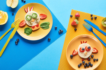 top view of plates with fancy animals made of food on blue and yellow background