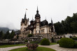 Famous Castle Peles in Sinaia as shot during a rainy day with moody sky and rolling fog (Sinaia, Romania, Europe)